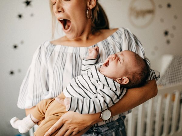 Mother and baby yawning together in a cozy nursery.