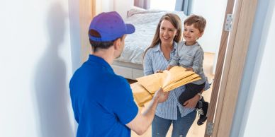 Repartidor entregando un paquete a madre e hijo.