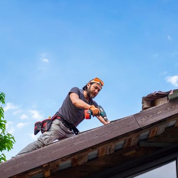 A man working on a roof using a power drill.