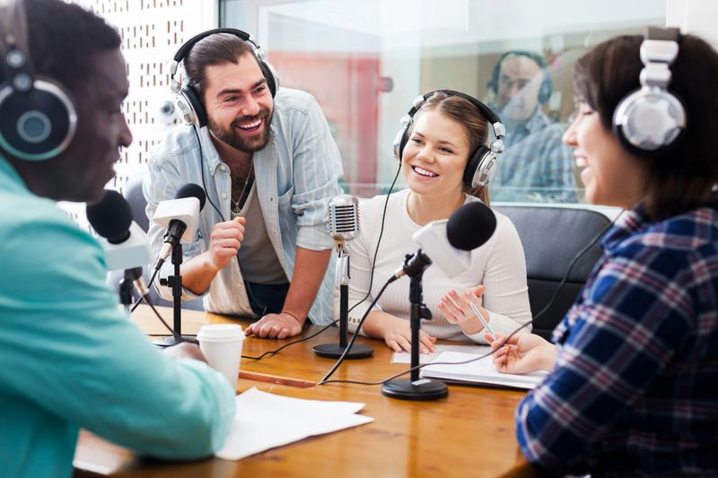 Smiling international team of radio presenters interviewing guest in studio