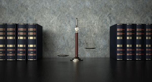 A balance scale between two sets of books on a desk.