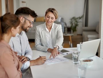 Three people discussing documents in a bright office setting.