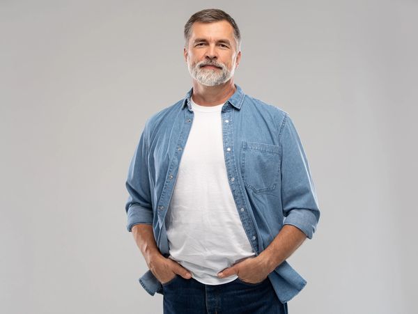 Confident middle-aged man with a beard wearing a denim shirt over a white t-shirt. Fresh out of the shower.