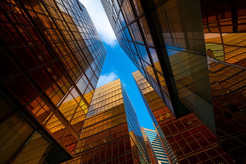 Low wide-angle view looking up to modern skyscrapers in business district on a beautiful sunny day with blue sky