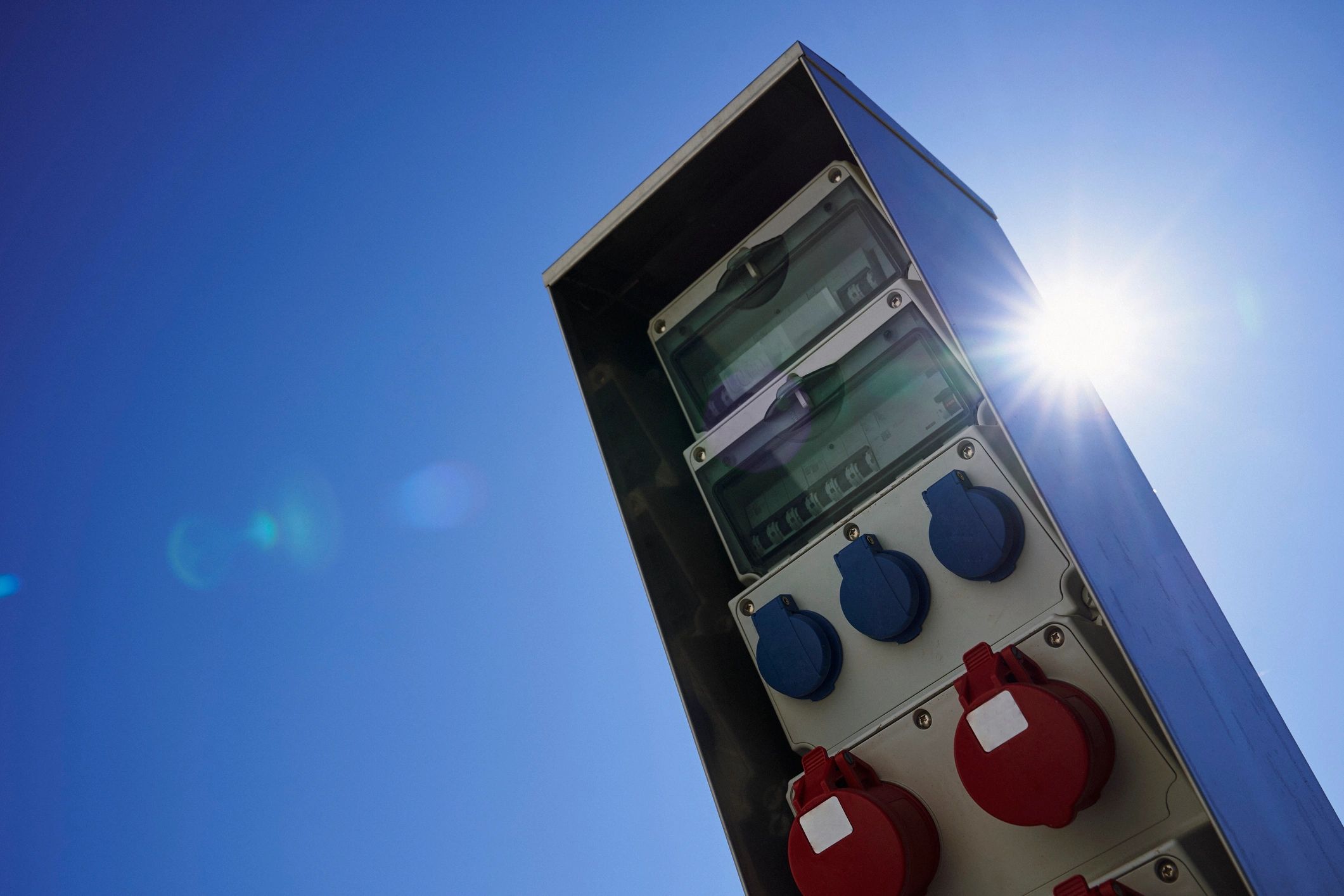 column with sockets against blue sky and lens flare