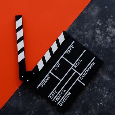 A black and white film clapperboard on a split orange and dark textured background.