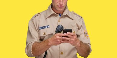 Sheriff in uniform focused on his phone against a yellow background.