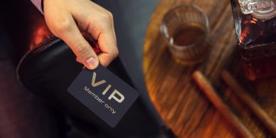 Hand holding a VIP card near a table with drinks.