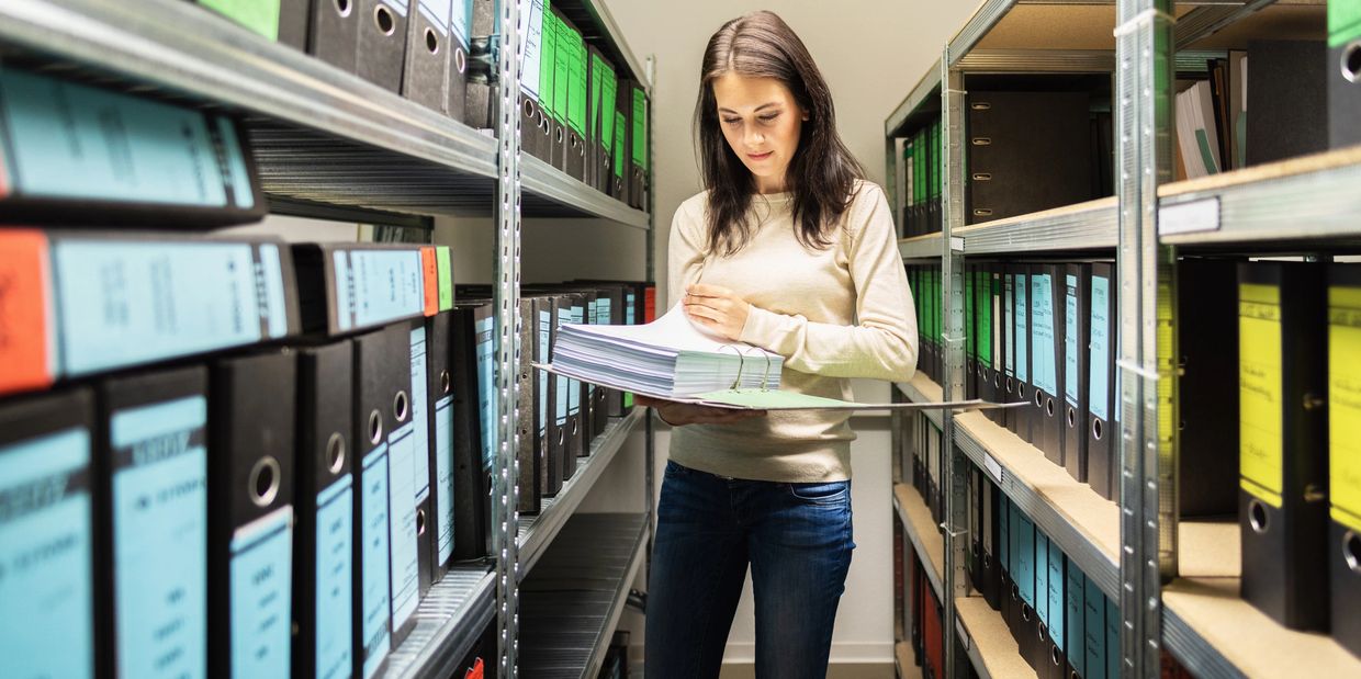 Woman organizing documents in a file storage room.