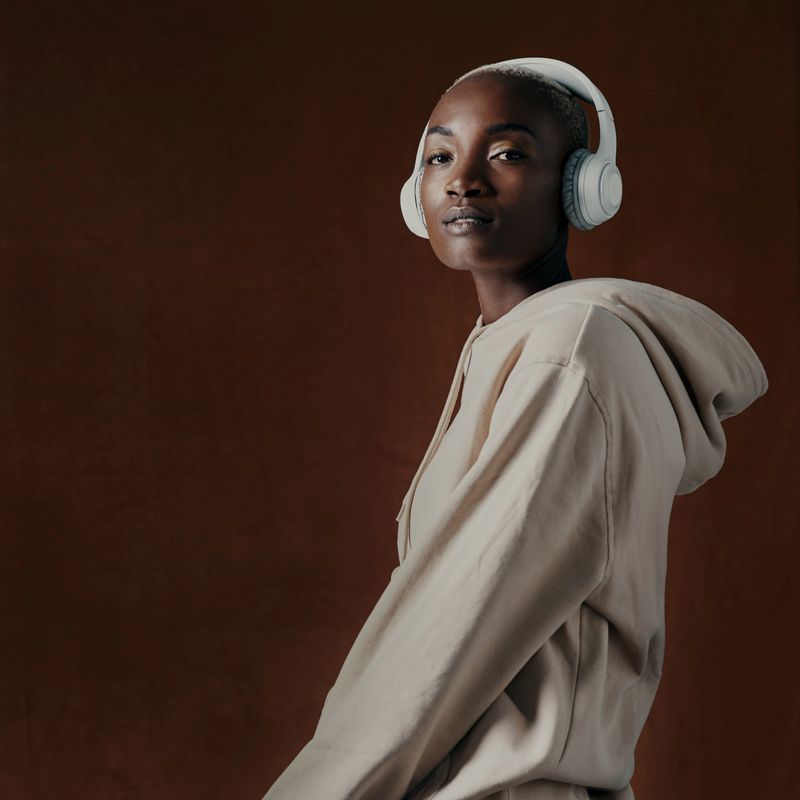 Studio portrait of an attractive young woman wearing headphones and posing against a brown background