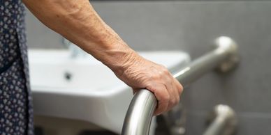 An OT client grasping a washroom grab bar while at the sink, representing home safety assessments