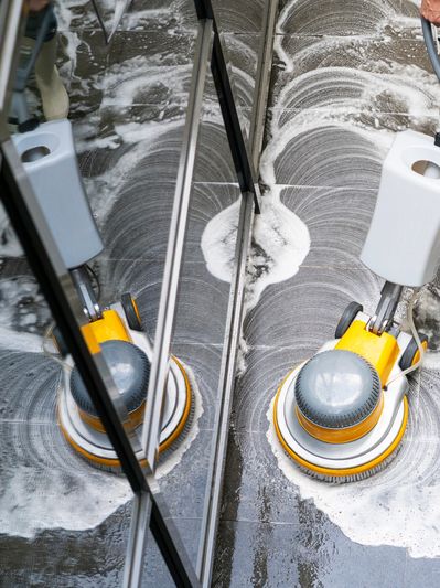 Floor cleaning machine scrubbing a soapy floor.