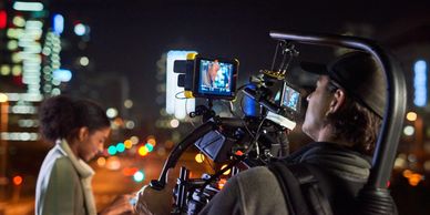 Cinematographer filming an actress at night in the city.