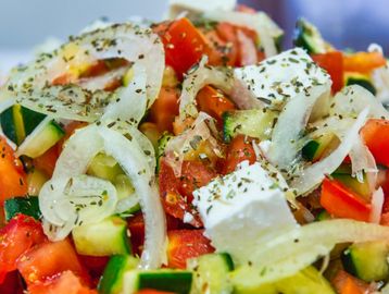 Close-up of a fresh Greek salad with onions, cucumbers, tomatoes, and feta cheese.
