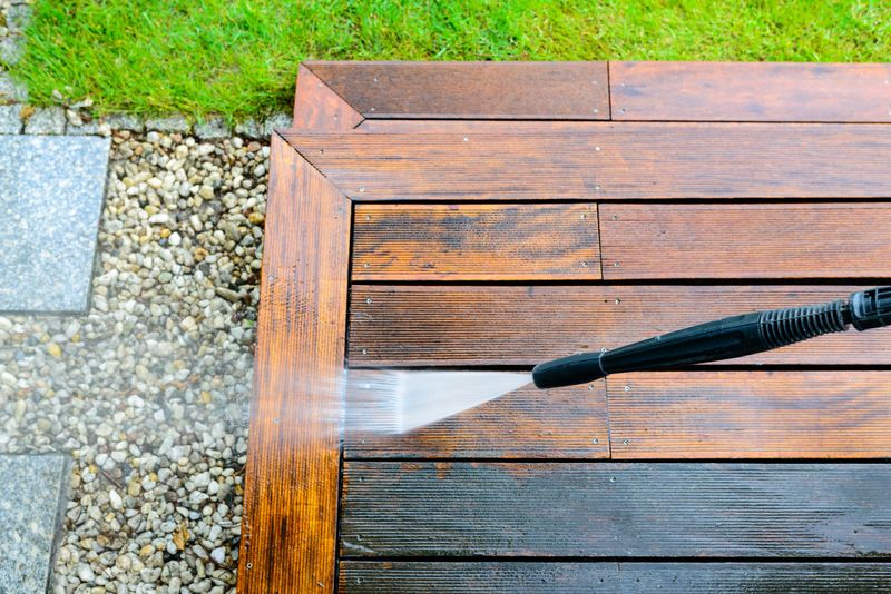 cleaning terrace with a power washer - high water pressure cleaner on wooden terrace surface - focus on the tip of the spray nozzle