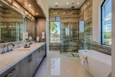 Modern bathroom with glass shower, freestanding tub, and large mirrors.