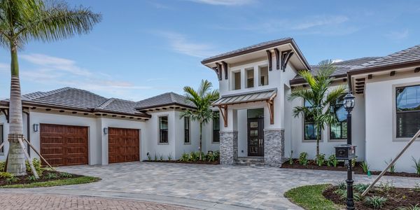 Modern house with stone accents and wooden garage doors under a clear blue sky.