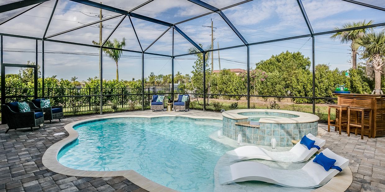 Luxury backyard pool inside a screened enclosure with spa, lounge chairs, and outdoor seating area