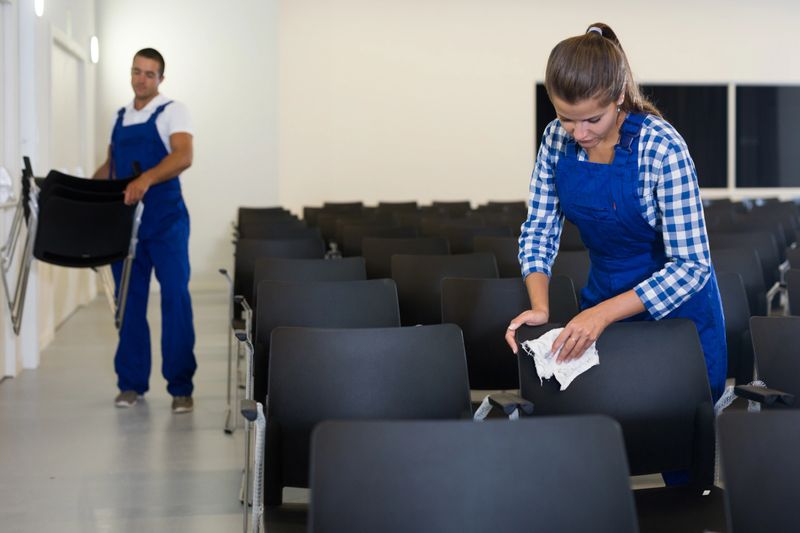 Male and female workers in uniform redecorating conference hall