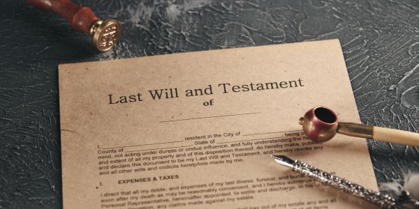Close-up of a last will and testament document with a wax seal stamp and pen.