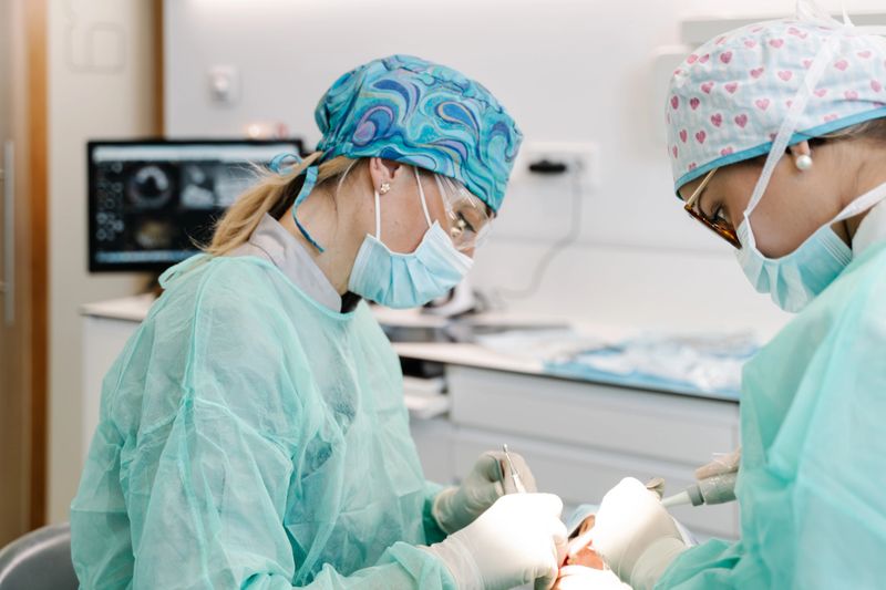 The assistant and the dentist talk to a patient during an operation