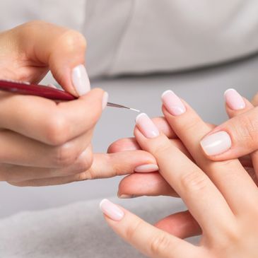 A close-up of a person receiving a manicure with a fine brush.