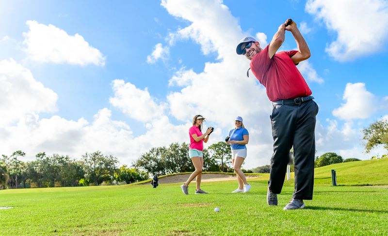 Man and two women female golfers in their thirties play golf on a beautiful clear sunny day with blue skies and soaring palm trees. Candid and happy sporty group on the golf course in Florida