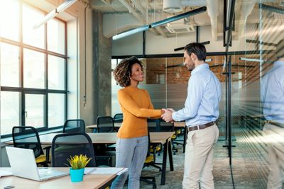 Two colleagues shaking hands in a modern office.