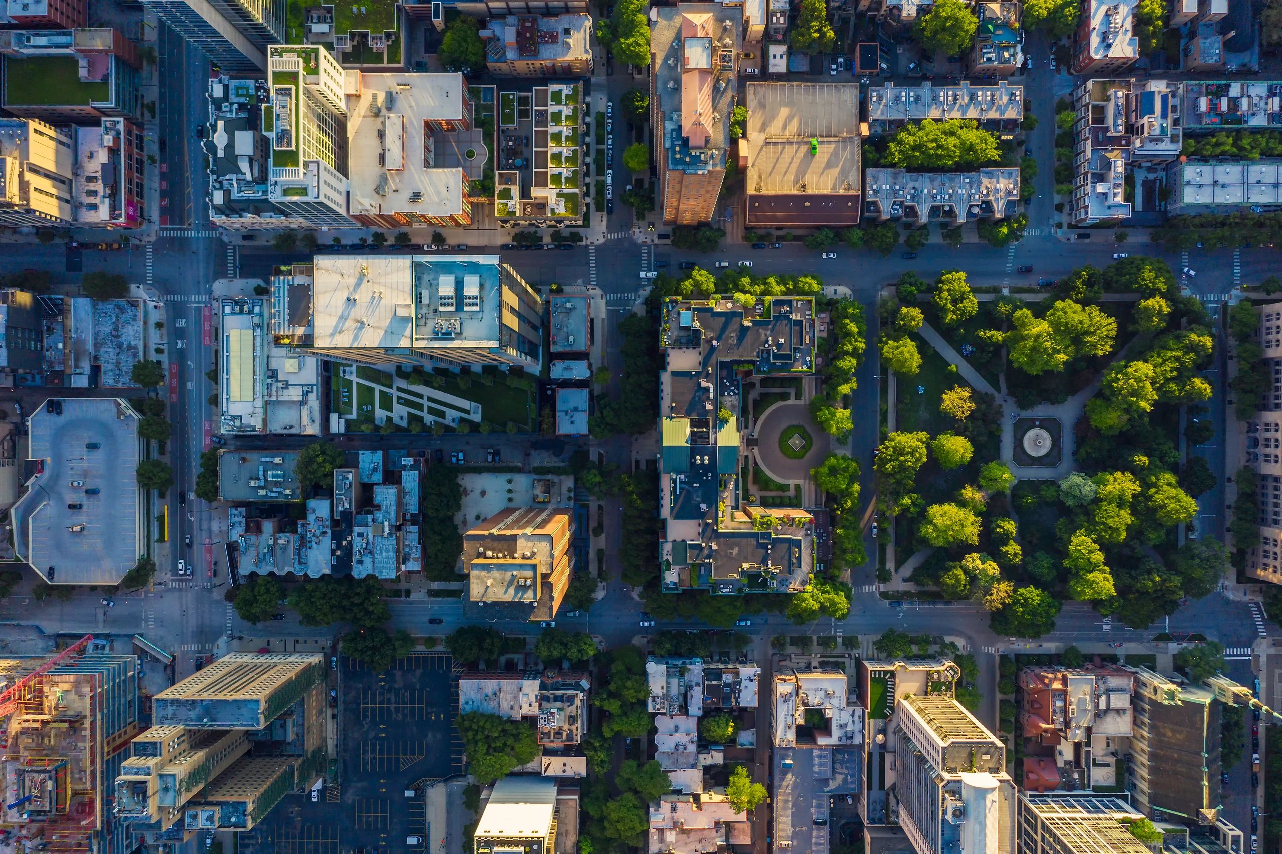 Aerial view of a city grid showing buildings, streets, and a large green park with trees.