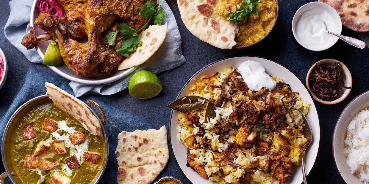 A vibrant Indian meal with grilled chicken, rice, naan, and various side dishes.