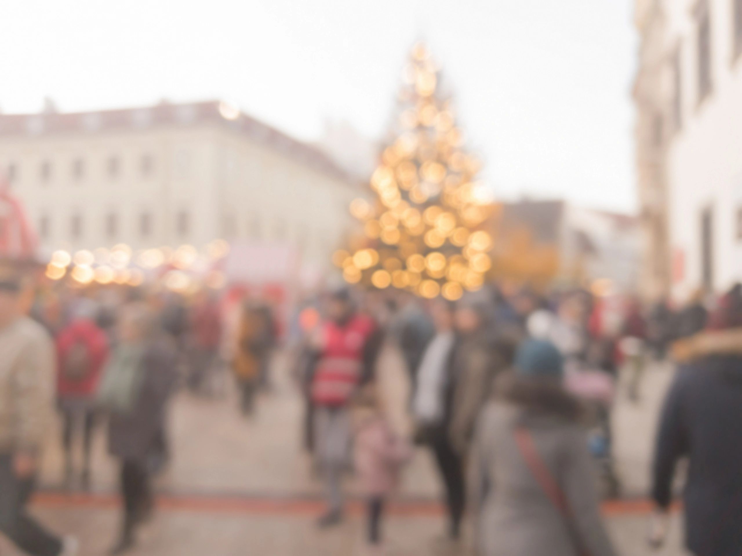 Blurred Christmas market with festive lights and crowd.
