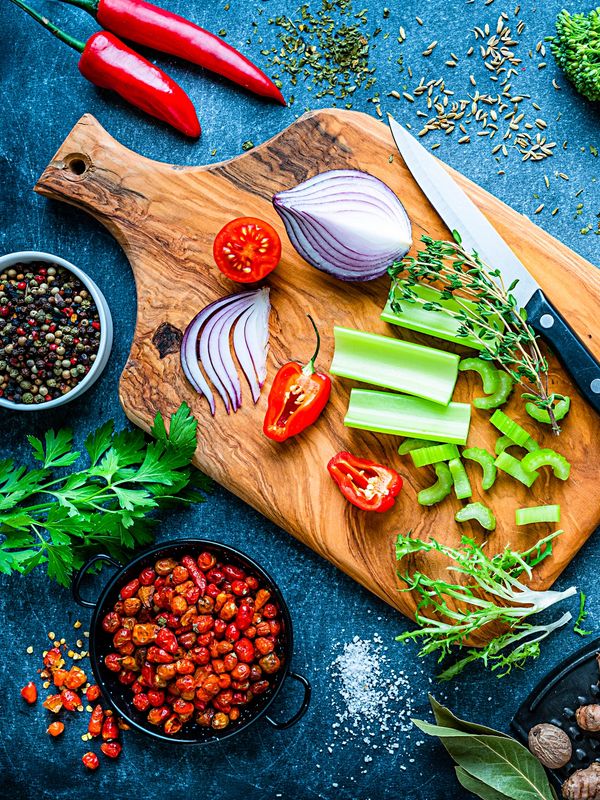 Fresh vegetables and spices on a wooden cutting board.