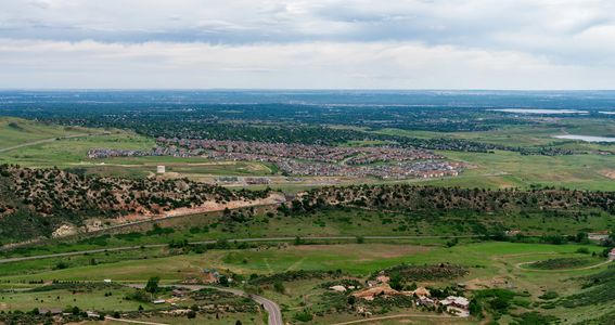 A panoramic view of a suburban area with green hills and cloudy sky.