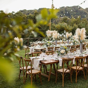 Outdoor wedding table setup featuring boho style, woodern chairs and feather centrepieces.