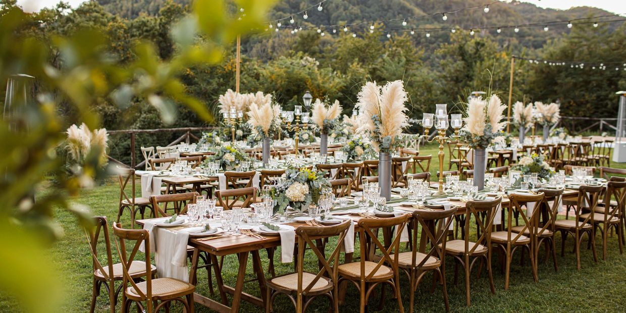 Elegant outdoor wedding tables with floral centerpieces and string lights.