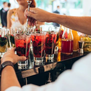 Bartender preparing red cocktails with berries and mint.