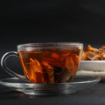 Glass cup of herbal tea with dried flowers.