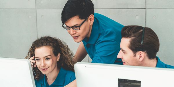 Tres jóvenes colaborando frente a una computadora.