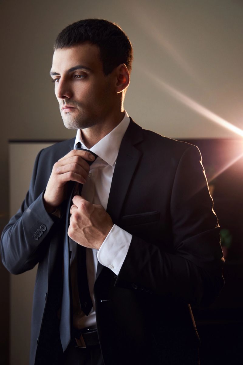 Portrait of a man in a suit and tie near the window. The groom is preparing for the wedding ceremony