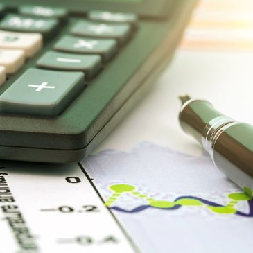 Close-up of calculator, pen, and financial chart on desk.
