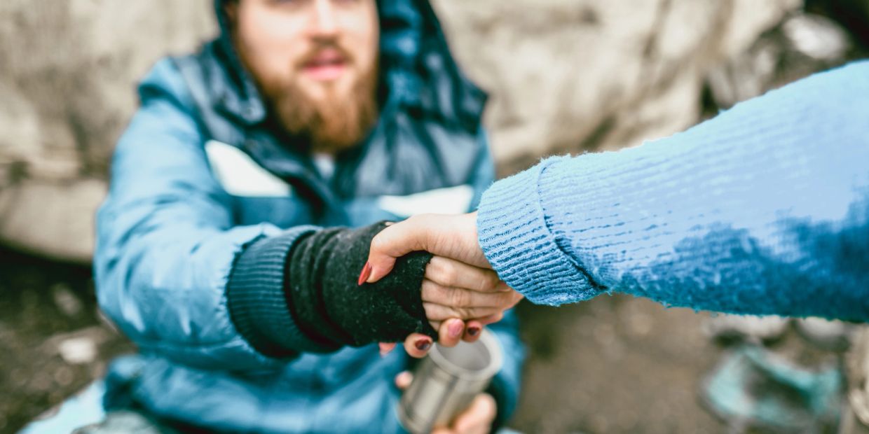 Person helping another by shaking hands in cold weather.