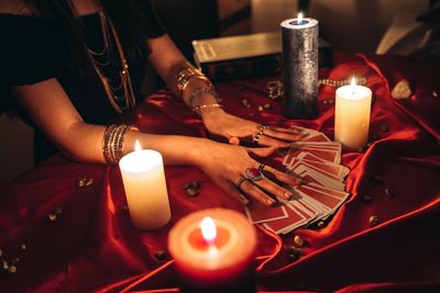 Fortune teller reading tarot cards by candlelight with mystical ambiance.