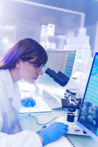 Scientist examining samples through a microscope in a laboratory.