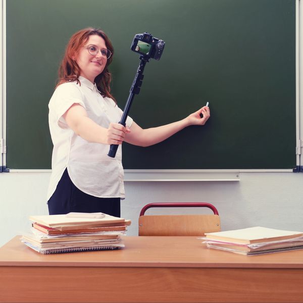 Teacher recording a video lesson in front of a chalkboard.