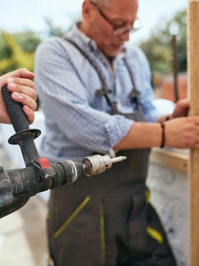 Professional from a fence company installing wood fence in backyard.