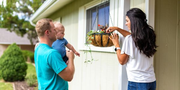 Family tending to hanging plant outside home.