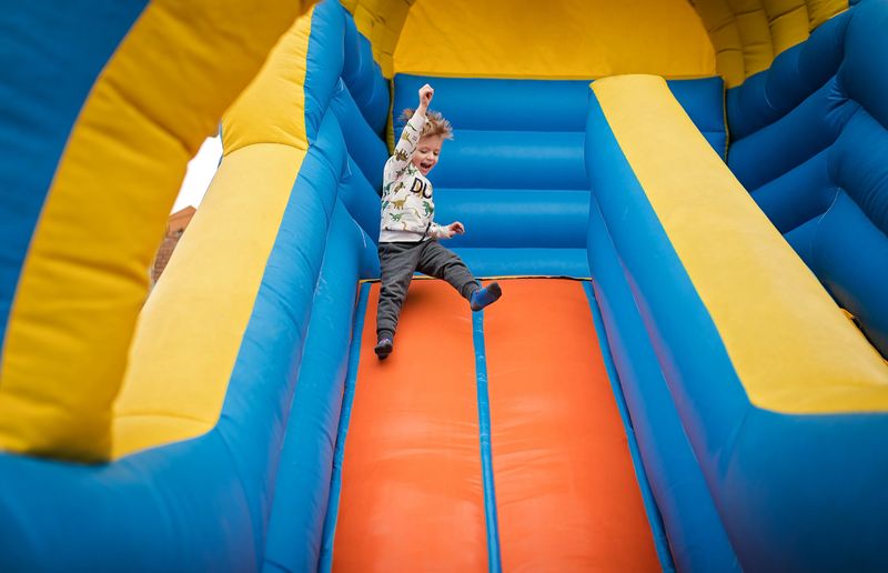 Happy little boy sliding down on a bouncy castle