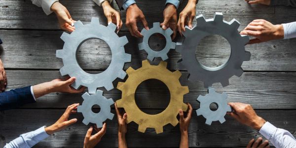 Hands holding interconnected gears on a wooden table.