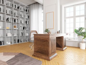 Bright home office with wooden desk, large windows, and tall bookshelves.