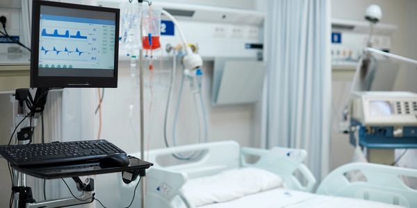 Empty hospital room with medical equipment and a patient bed.